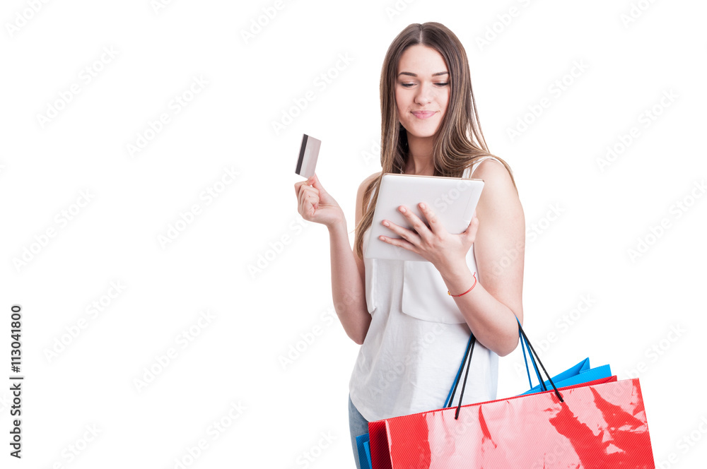 Attractive young shopaholic looking on digital tablet and carryi Attractive young shopaholic looking on digital tablet and carryi