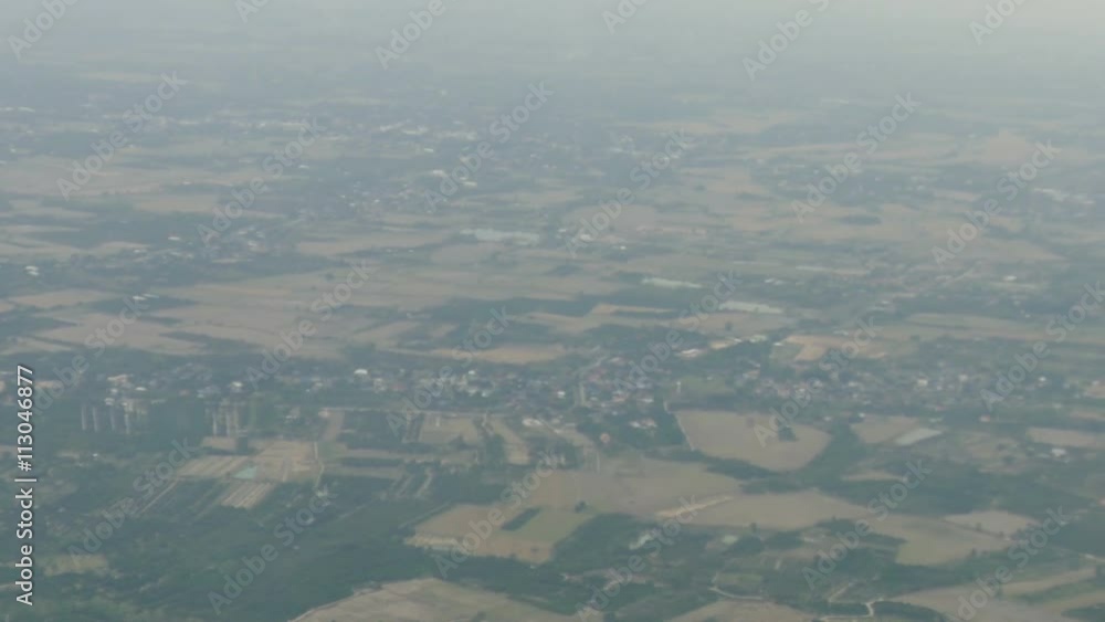 view of residential area and rice paddy field in rural thailand in foggy day from airplane window view of residential area and rice paddy field in rural thailand in foggy day from airplane window