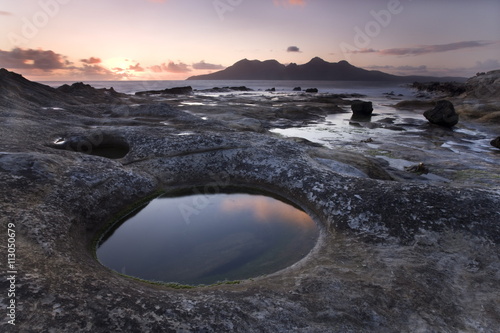 View towards Isle of Rum at sunset from rock formation at Laig Bay, Isle of Eigg, Inner Hebrides, Scotland photo