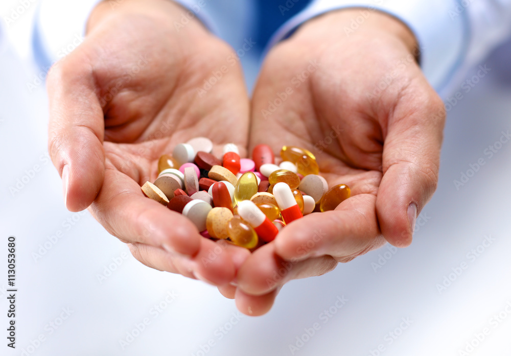 A young doctor holds the patient's hand with pills