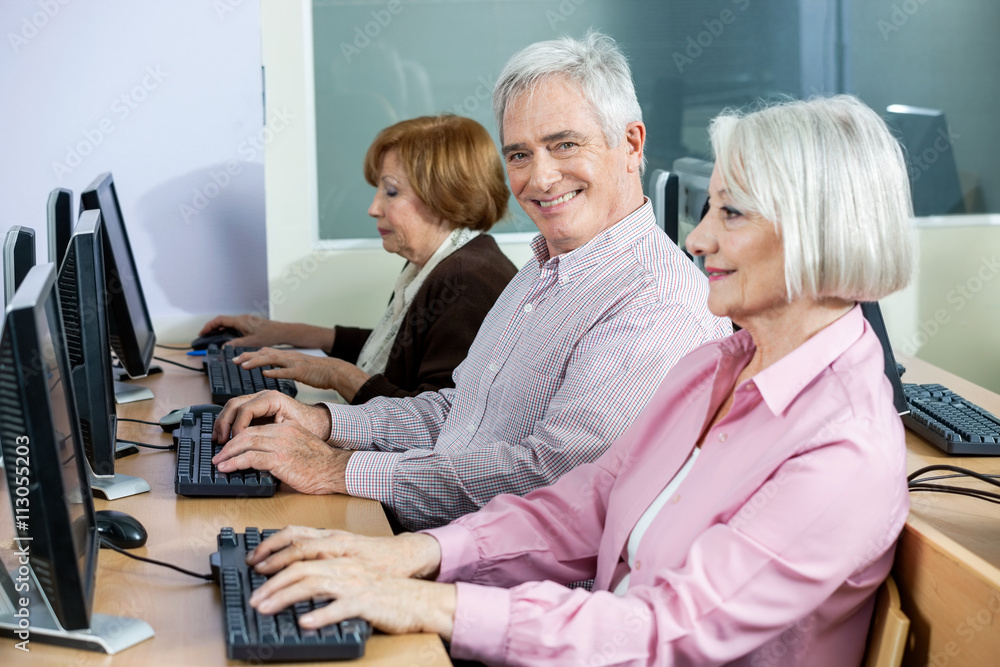 Happy Senior Man Sitting At Desk In Computer Class Happy Senior Man Sitting At Desk In Computer Class