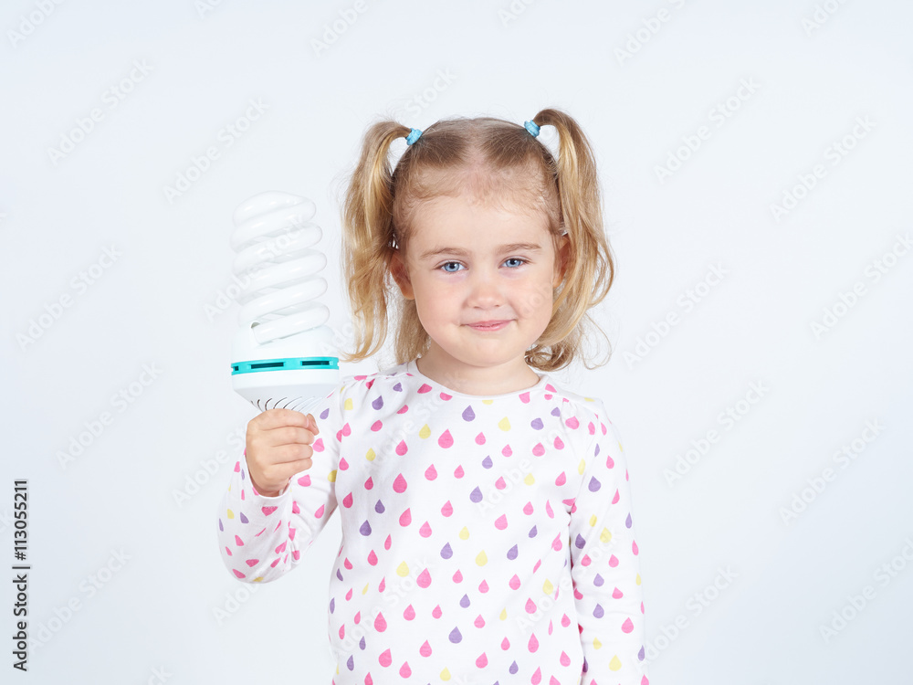 Little girl shows a large energy-saving light bulbs. Little girl shows a large energy-saving light bulbs.