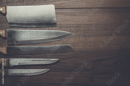 five kitchen knifes on the brown wooden background