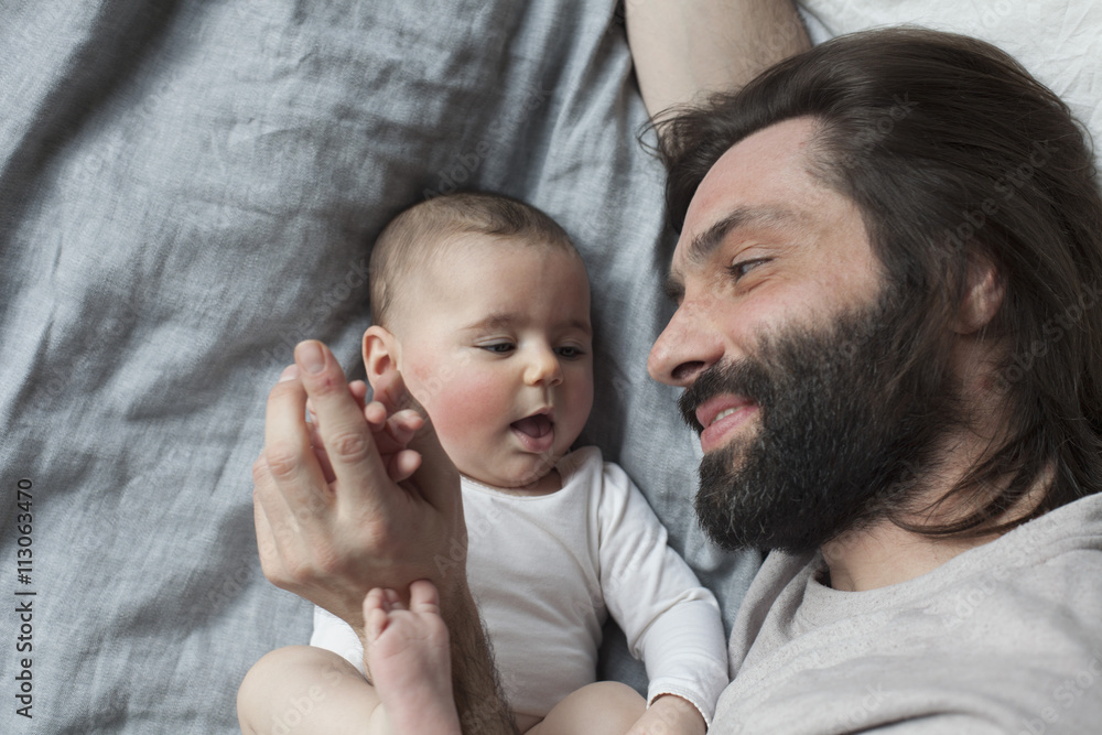 High angle view of affectionate father and baby girl in bed High angle view of affectionate father and baby girl in bed