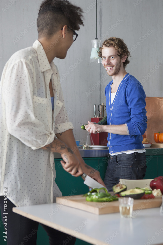 Smiling man preparing food with female friend in kitchen