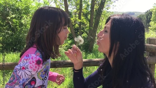 Mother and Daughter blowing on Dandelium, slow motion. photo