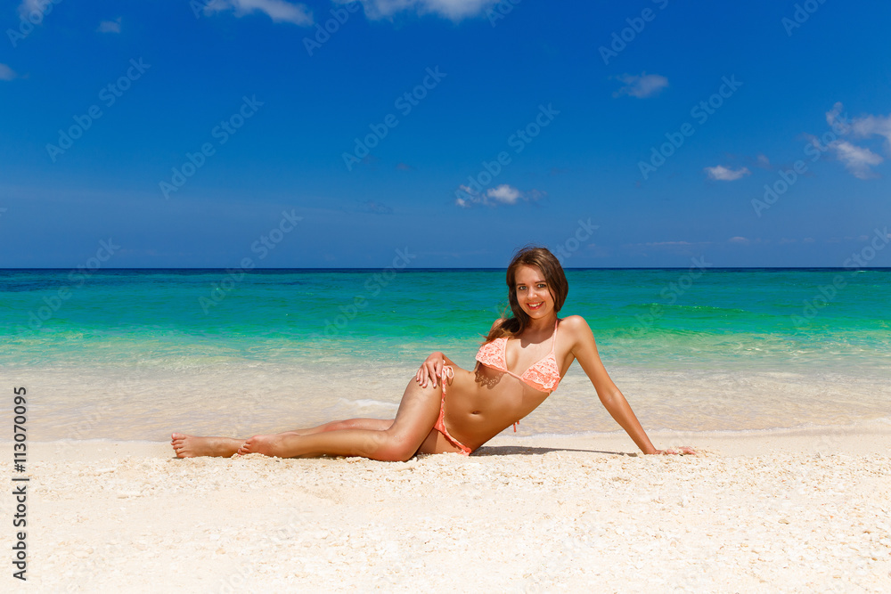 Happy beautiful young girl in bikini on a tropical beach. Blue s Happy beautiful young girl in bikini on a tropical beach. Blue s