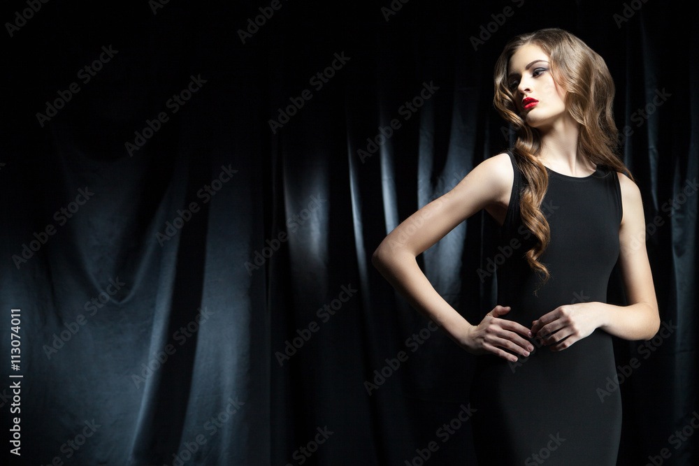elegant woman with long wavy hair against of black cloth