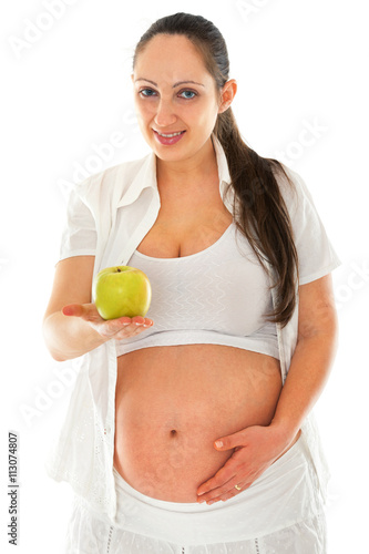 Pregnant young woman holding apple and looking at the camera. Isolated on white background © ivanmateev