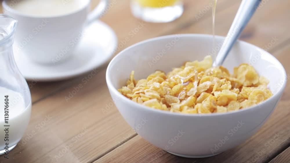 hand adding honey to corn flakes for breakfast hand adding honey to corn flakes for breakfast
