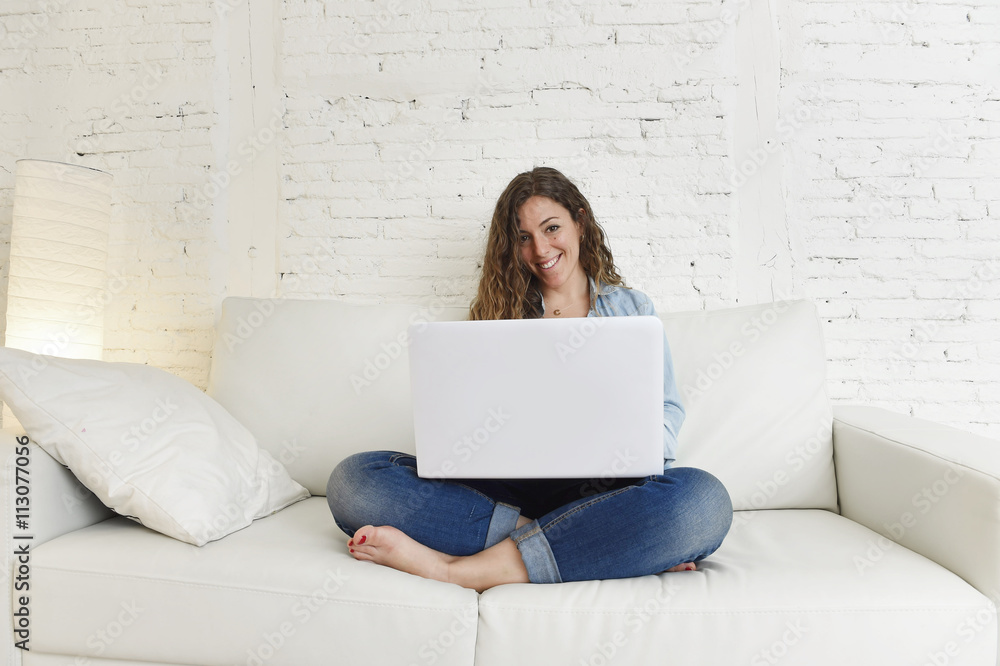 Fototapeta premium young attractive spanish woman using laptop computer sitting relaxed working on home couch