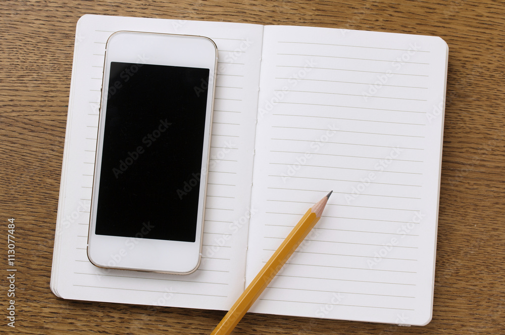 notebook and phone with blank screen on wooden table notebook and phone with blank screen on wooden table