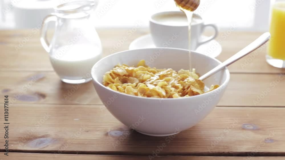 hand adding honey to corn flakes for breakfast hand adding honey to corn flakes for breakfast