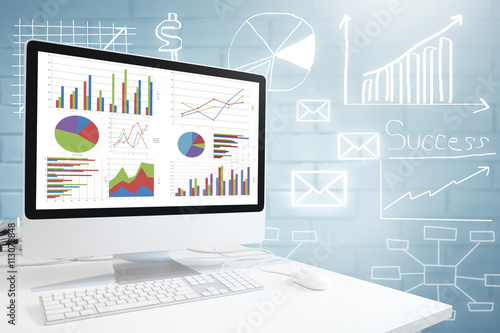 Modern computer with keyboard and mouse on table showing charts