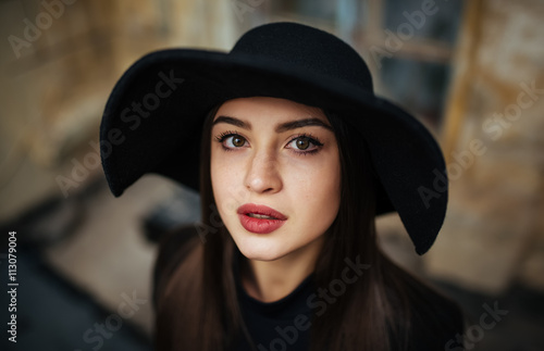 Street portrait of young casual lady in hat, black clothes, red lips
