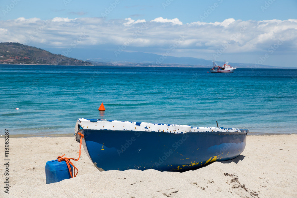 A yaucht in the turquoise sea waters and a blue boat on the white sand A yaucht in the turquoise sea waters and a blue boat on the white sand