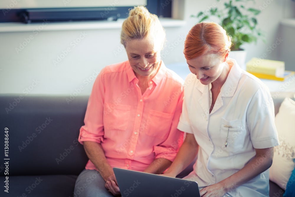 Fototapeta premium Female nurse and senior woman using laptop