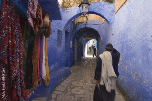 Man walking through pastel coloured streets of Chefchaouen, Morocco photo