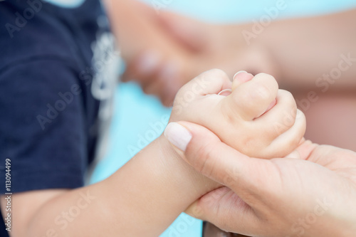 Toddler baby holding his mothers finger. Selective focus