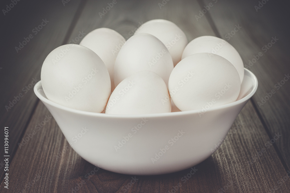some eggs in white bowl on wooden table