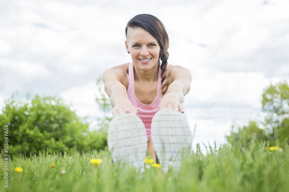 Young female athlete excercising and stretching in a park Young female athlete excercising and stretching in a park