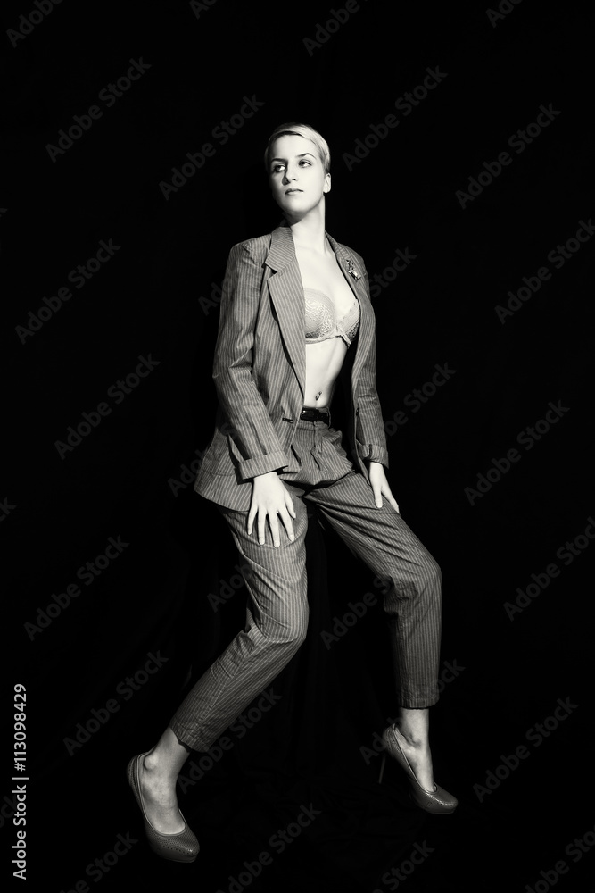 Fototapeta premium Young woman in suit and bra on black background