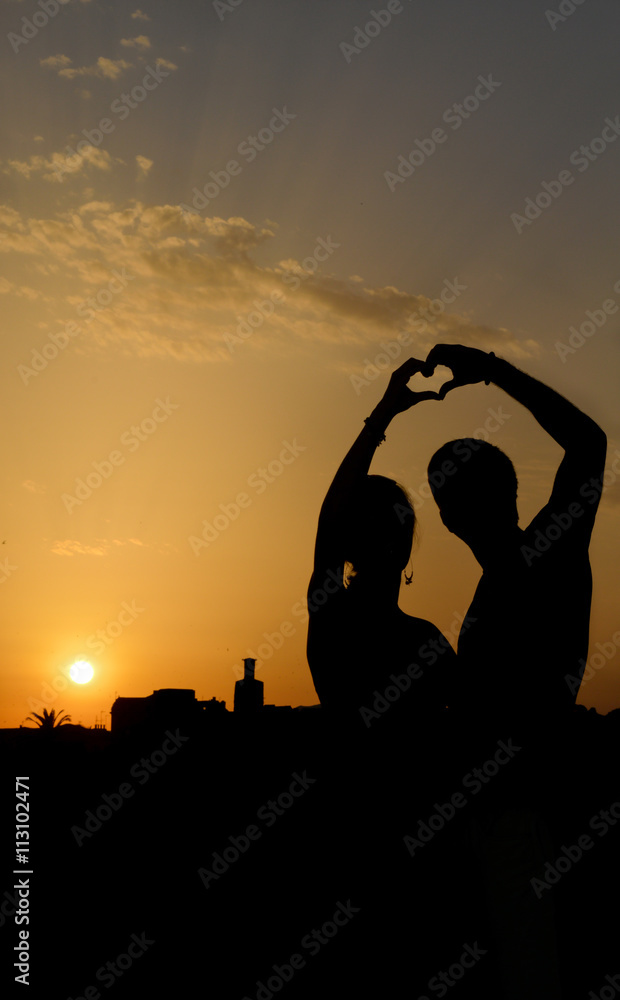 Silhouette of a couple making heart shape