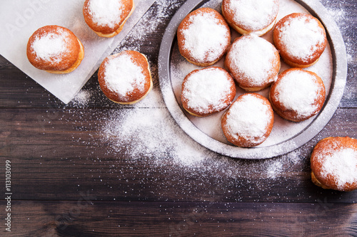 German donuts - berliner with jam and icing sugar in a tray on a wooden background. Top view photo