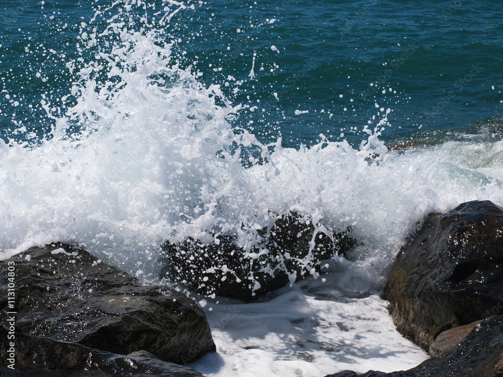 Fototapeta premium Sea wave crashing on rocks on the beach