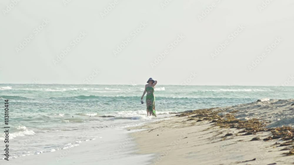 Young woman In long Dress keeps the shoes and Walking along the sea Young woman In long Dress keeps the shoes and Walking along the sea