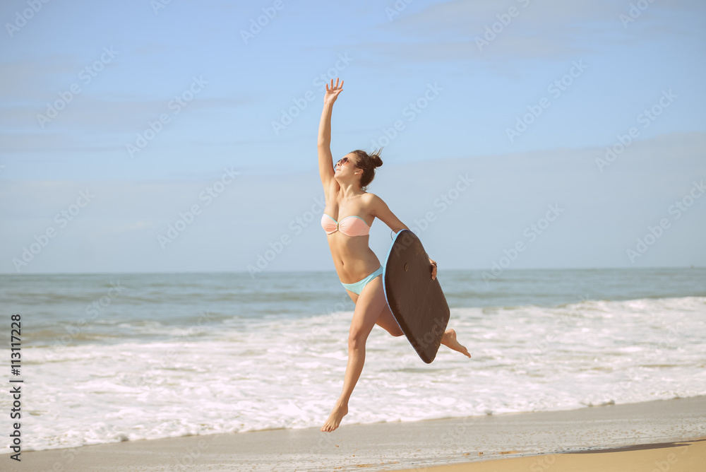 Joyful surfer girl happy cheerful running surfing at ocean beach water. Female bikini heading for waves with surfboard 