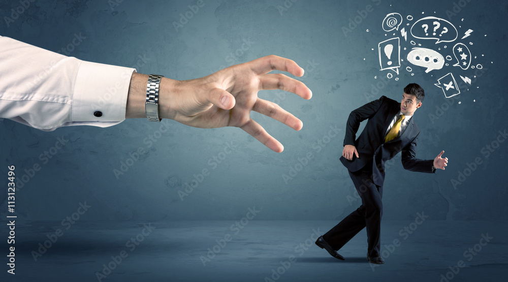 Business man running from a big hand