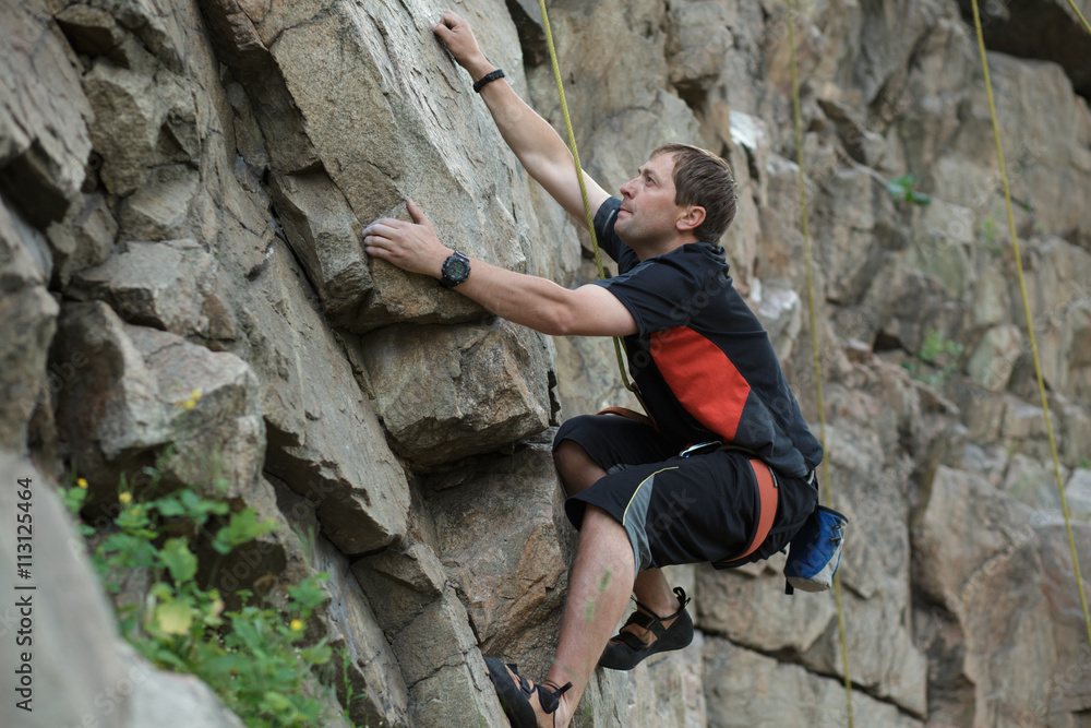 Male rock climber clings to a cliff Male rock climber clings to a cliff
