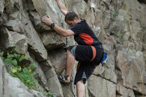 Male rock climber clings to a cliff