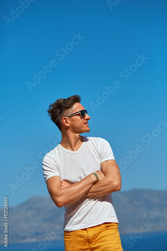 male traveler on the cliff against blue sky and sea