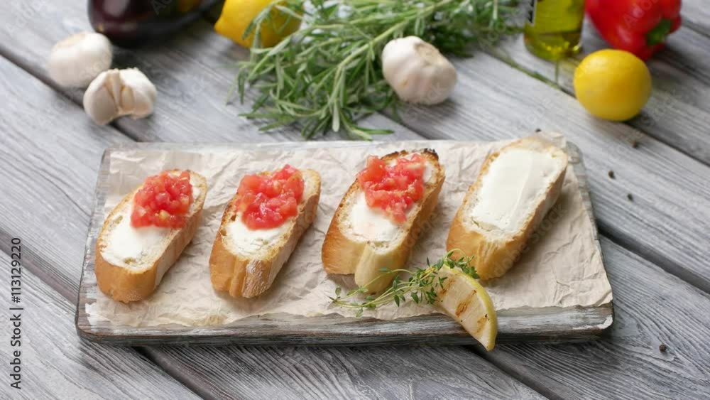 Spoon puts vegetables on sandwich. Piece of lemon beside toasts. Bruschetta with baked tomatoes. Delicious food for a gourmet. Spoon puts vegetables on sandwich. Piece of lemon beside toasts. Bruschetta with baked tomatoes. Delicious food for a gourmet.
