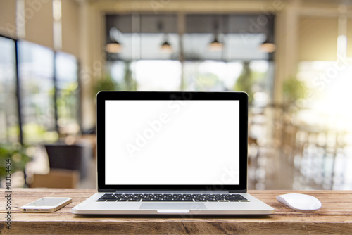 Laptop with blank screen on table of a cafe