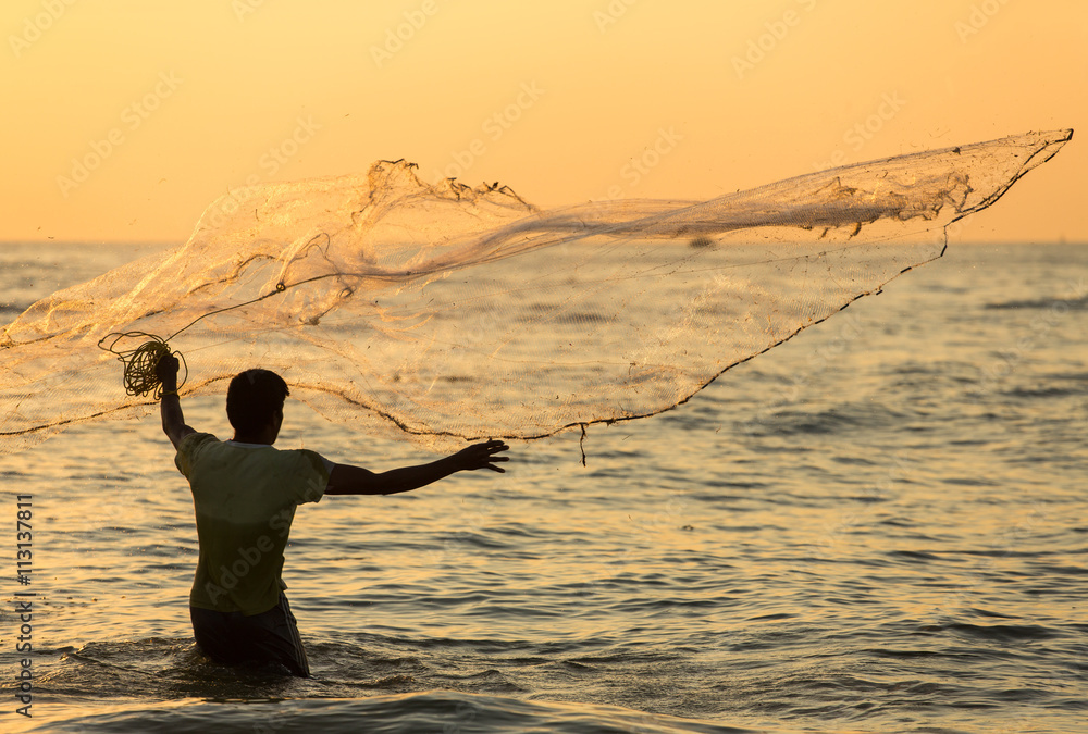 Φωτογραφία Silhouette of the unidentified Indian fisherman throwing net in sea on sunset in Fort Kochi, India
