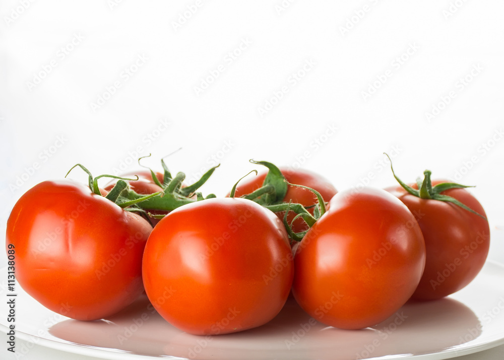 Ripe tomatoes on plate bowl on white background, horizontal imag Ripe tomatoes on plate bowl on white background, horizontal imag