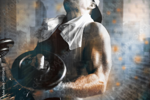 Fotografie Guy in the baseball cap raises a pair of dumbbells in the gym