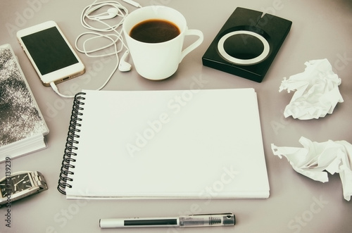 Business workplace. Top view of grey office desk with coffee cup, diary, notepad, pen, memory disk, smartphone and earphone. Copy space.