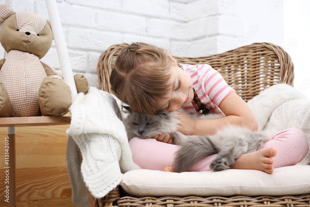 Little girl and cat on wicker armchair in living room Little girl and cat on wicker armchair in living room