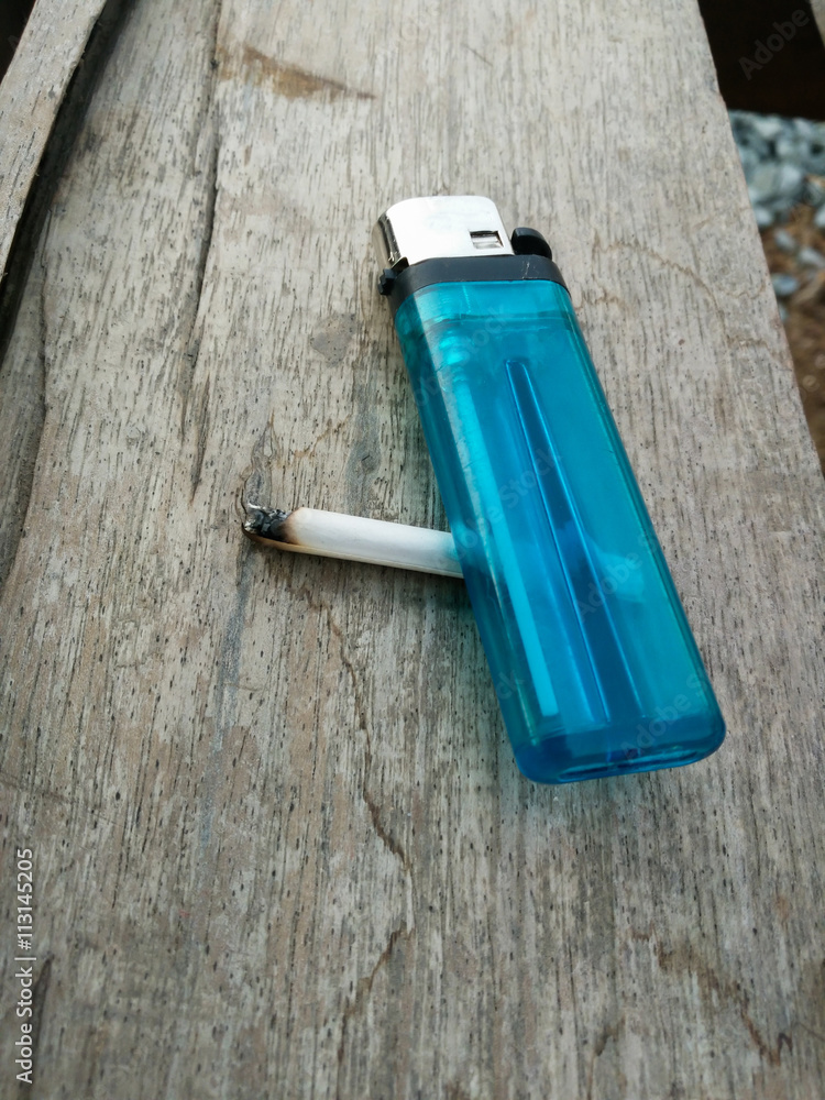blue lighter and Cigarette on the wood table