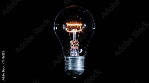 Tungsten light bulb lamp blinking over black background, macro view, loop ready