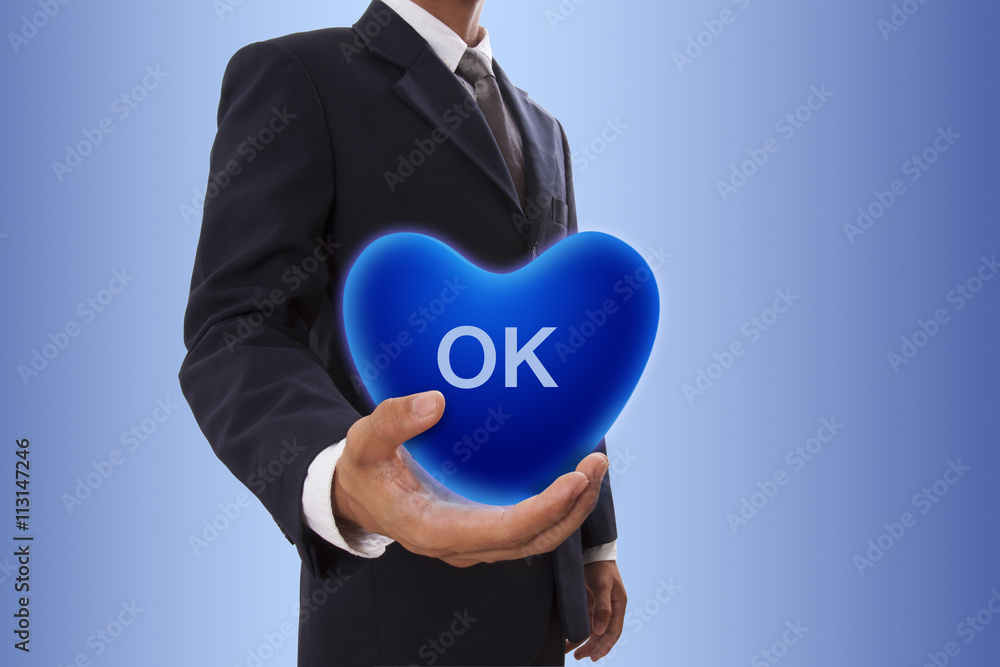 Businessman hand holding blue heart bubble with ok sign Businessman hand holding blue heart bubble with ok sign