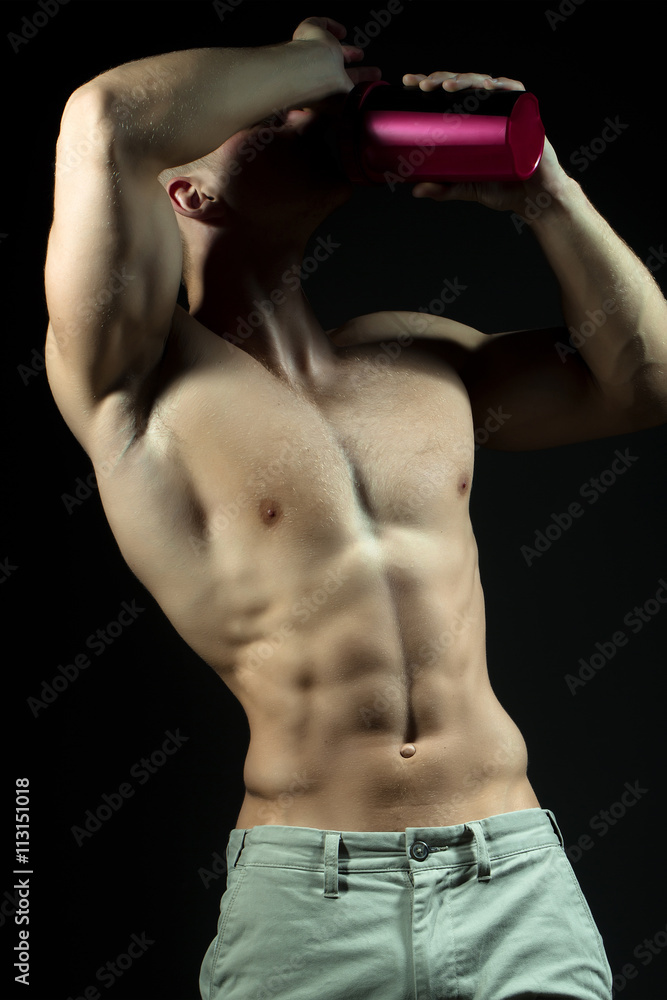Naklejka premium Muscular man drinking from cup