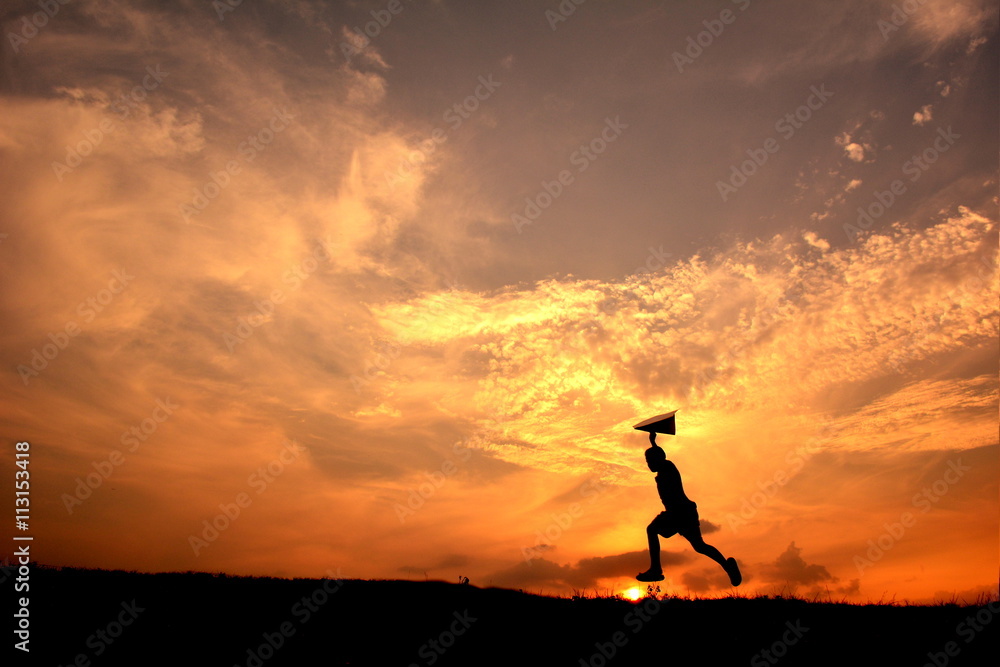 Silhouette boy holding rocket in the sunset. Concept big dream