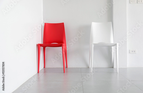 Fototapeta Naklejka Na Ścianę i Meble -  Red and white plastic chairs at the corner of the white room.