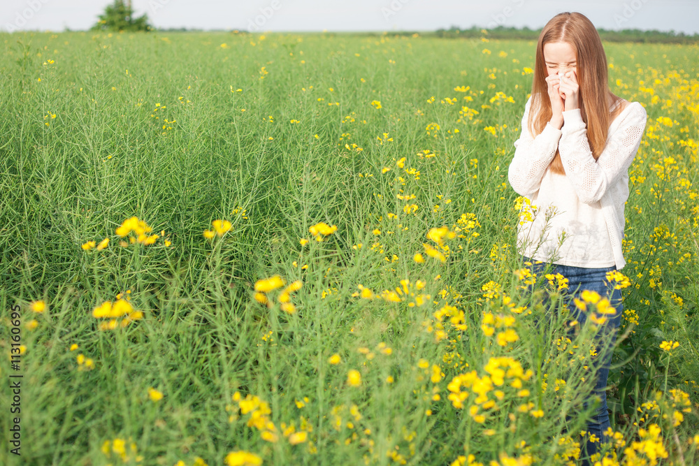 Pollen allergy, girl sneezing in a rapeseed field of flowers Pollen allergy, girl sneezing in a rapeseed field of flowers