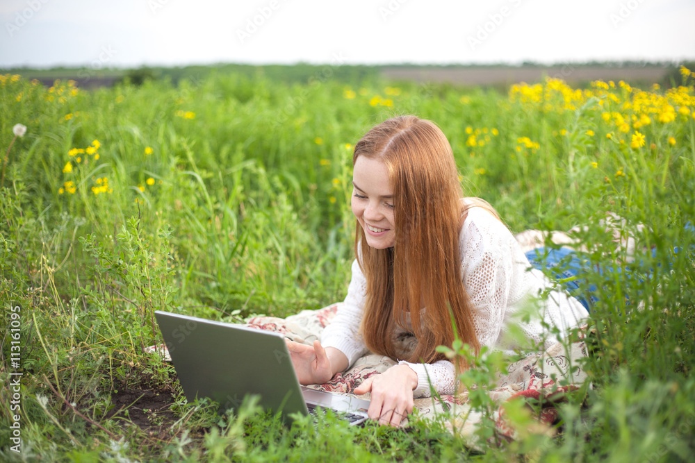 Young smiling woman with notebook in park looking at notebook computer Young smiling woman with notebook in park looking at notebook computer